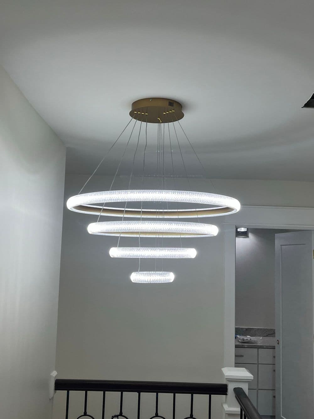 Modern multi-ring chandelier overhead, illuminating a stairwell with sleek design elements.