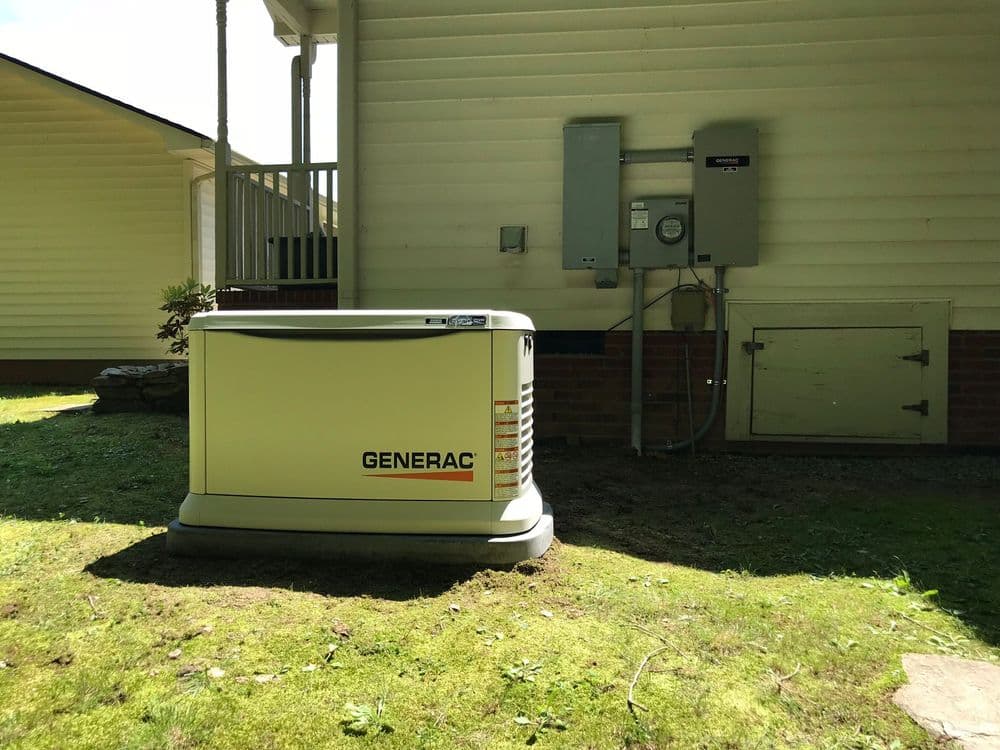 Generac home standby generator installed next to a house on a grassy lawn.