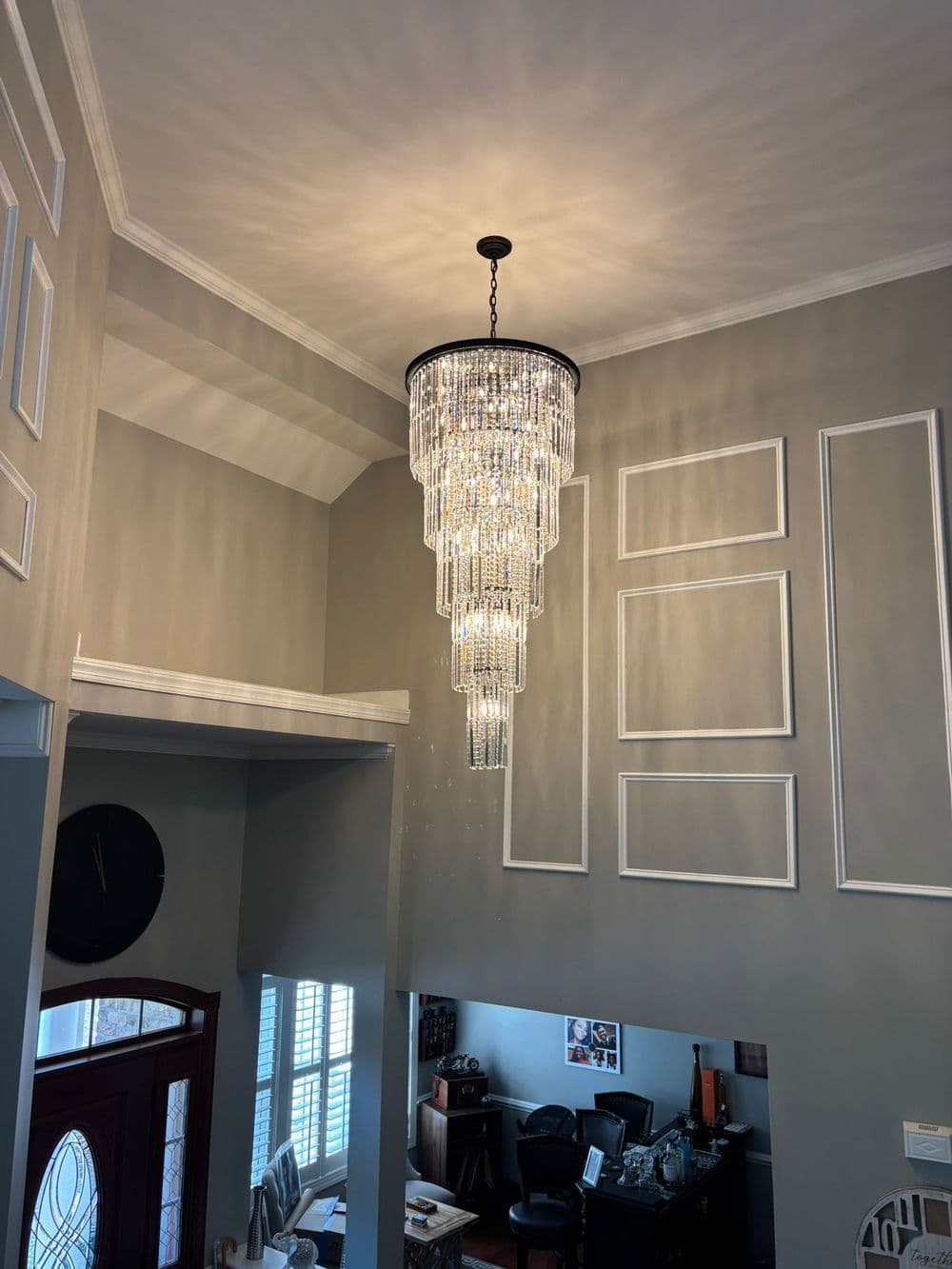Elegant crystal chandelier hanging from a high ceiling in a modern living space.