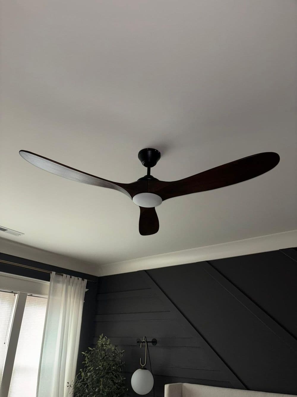 Modern ceiling fan with wooden blades and integrated light fixture in a stylish living room.
