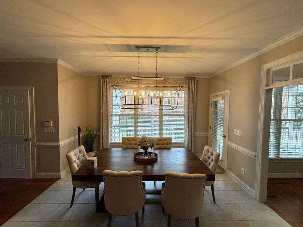 Modern dining room with a wooden table, elegant chairs, and natural light from large windows.