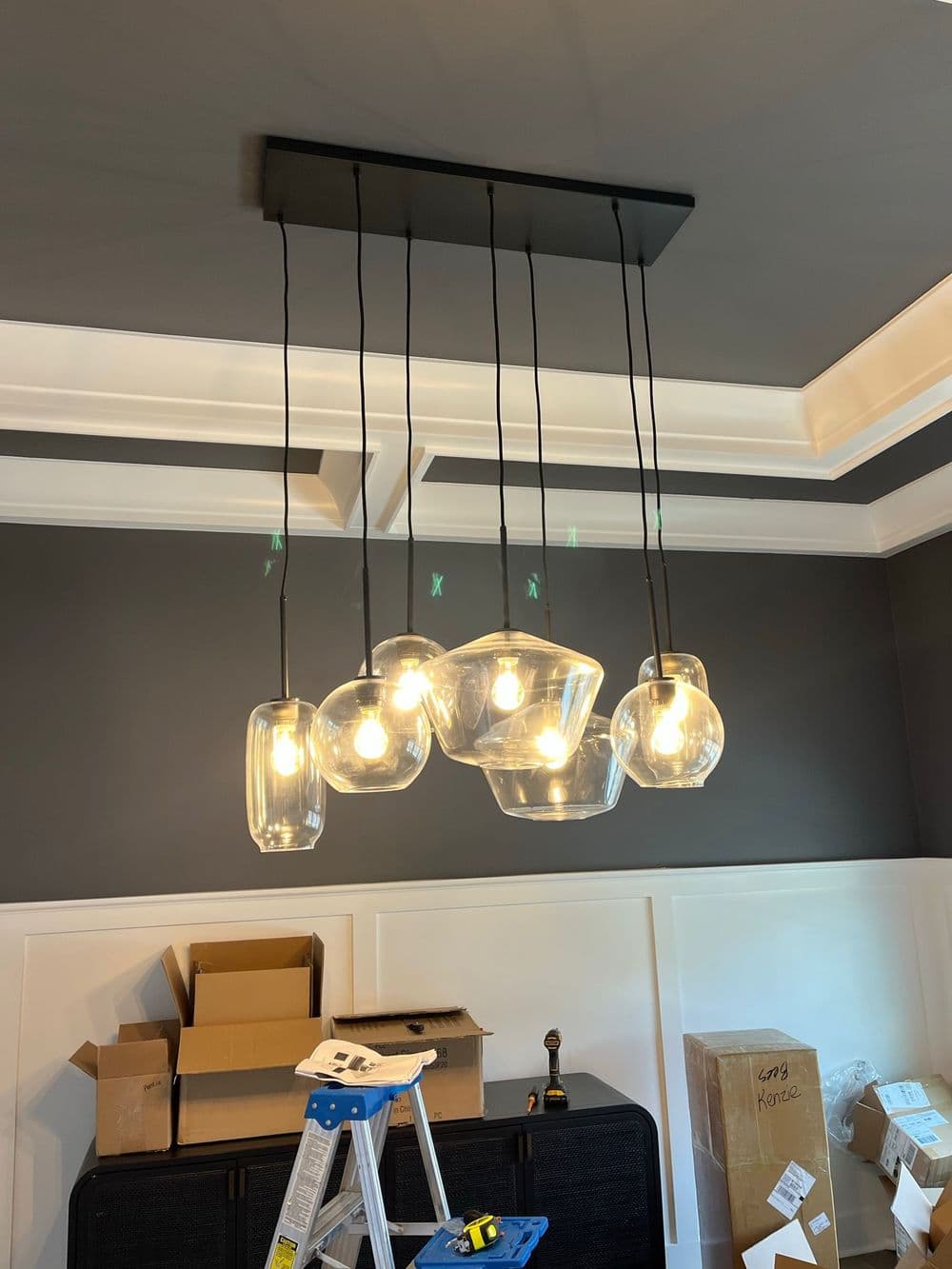 Modern glass pendant lights hanging from a ceiling in a stylish room with a dark gray wall.