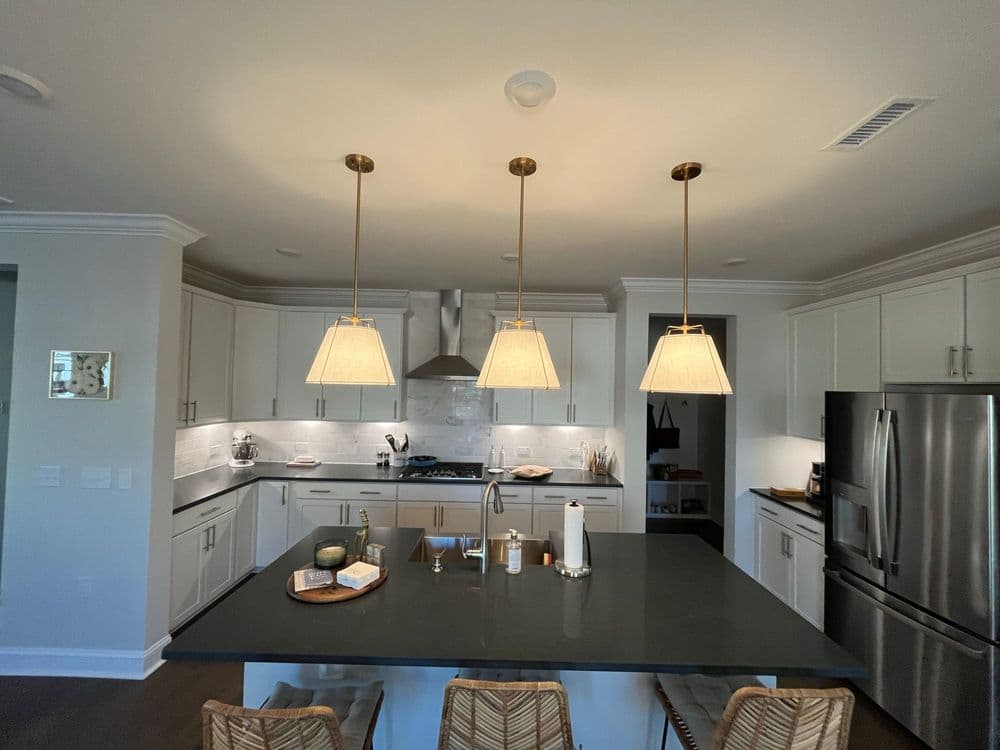 Bright modern kitchen with white cabinetry, granite island, and elegant pendant lighting.