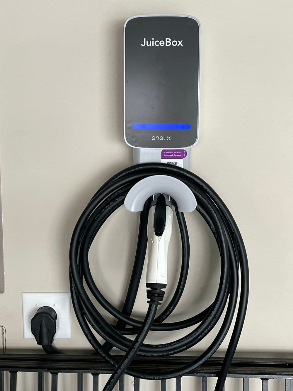 JuiceBox electric vehicle charger mounted on a wall with charging cable neatly organized.