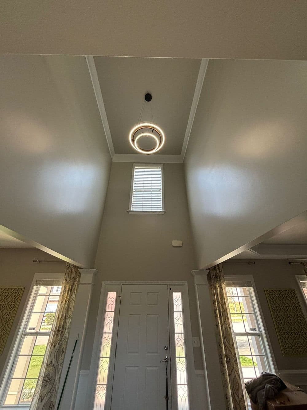 Modern entryway with high ceilings, circular chandelier, and large windows for natural light.