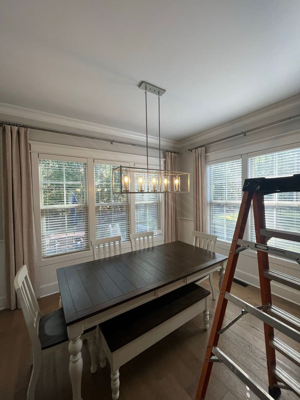 Modern dining room with a wooden table, elegant light fixture, and large windows.