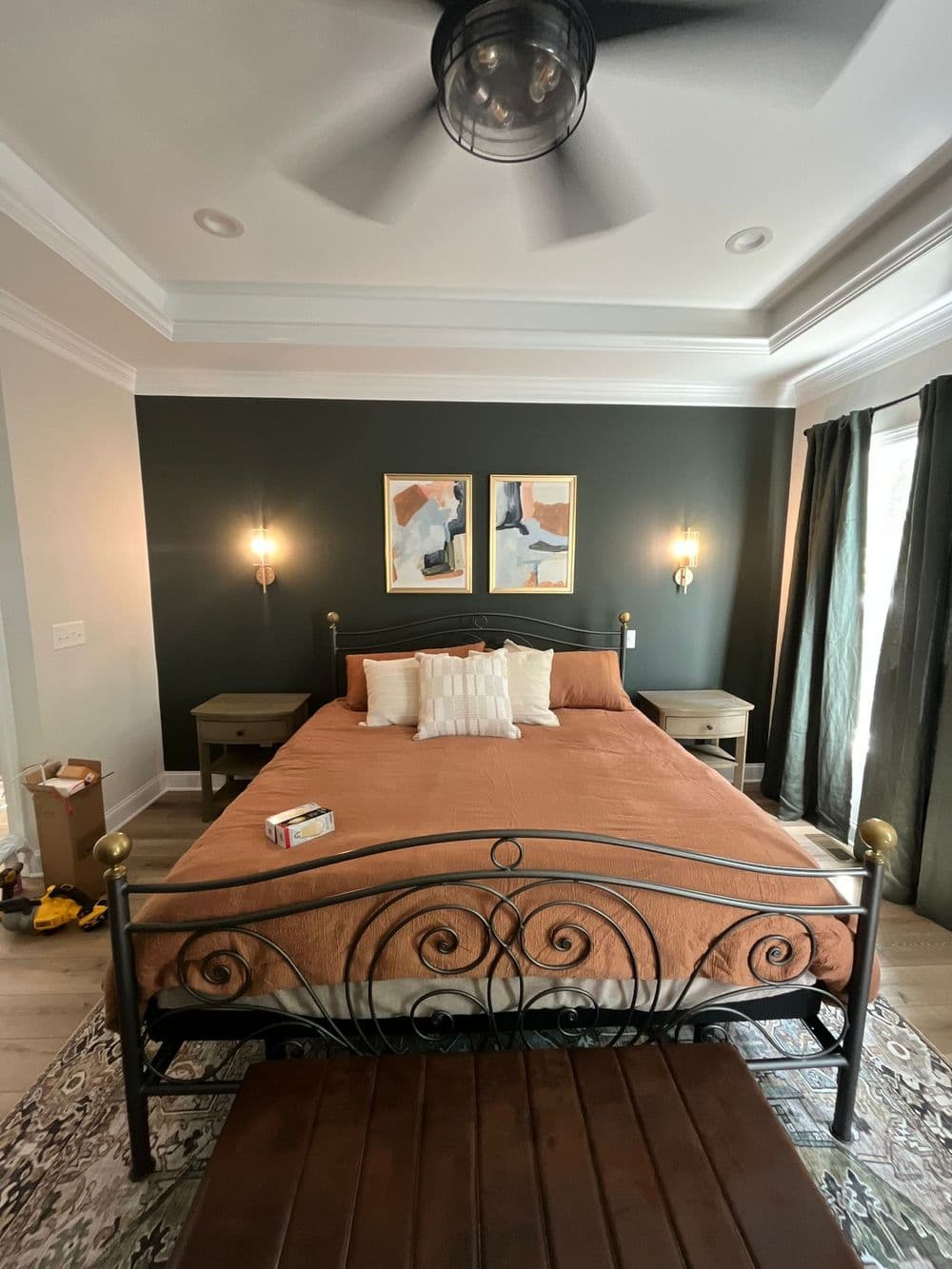 Cozy bedroom with a brown bedspread, wall art, and dark green accent wall.