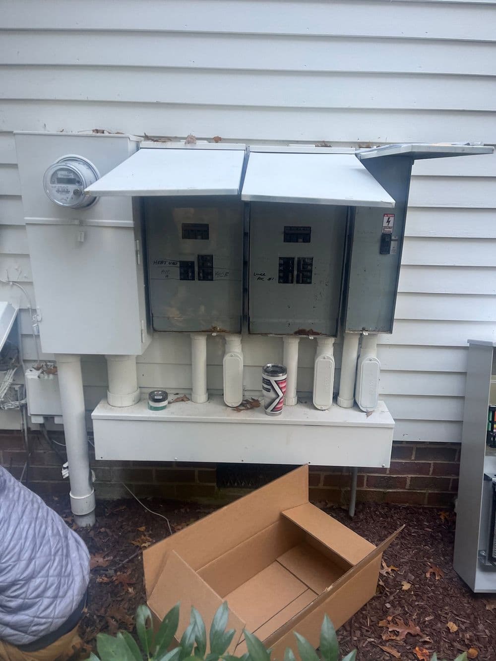 Utility meter bank mounted on exterior wall, featuring three meter boxes and electrical connections.