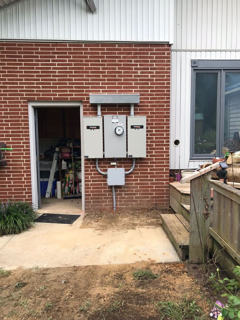 Electrical meters mounted on brick wall near entrance of a residential building.