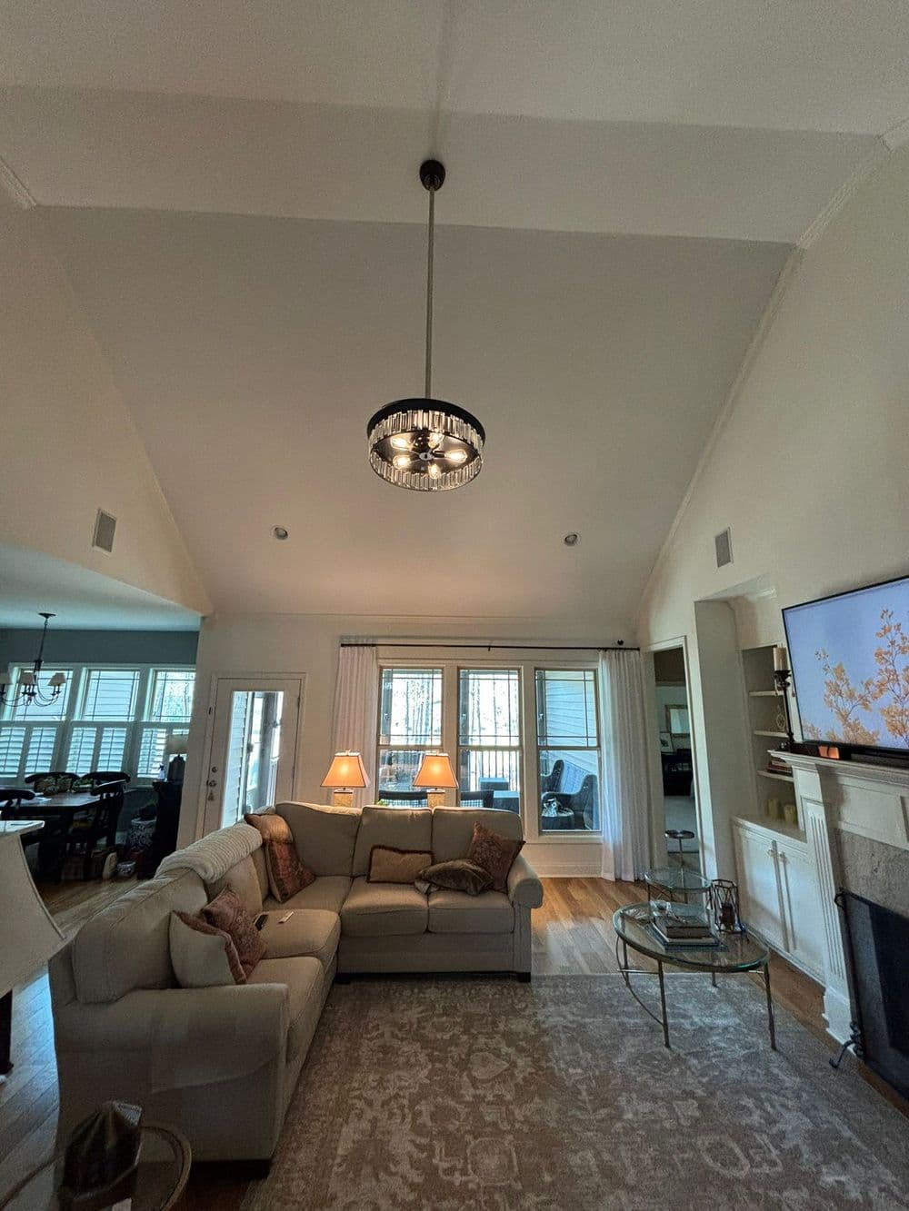 Modern living room with high ceiling, elegant chandelier, and stylish sofa.