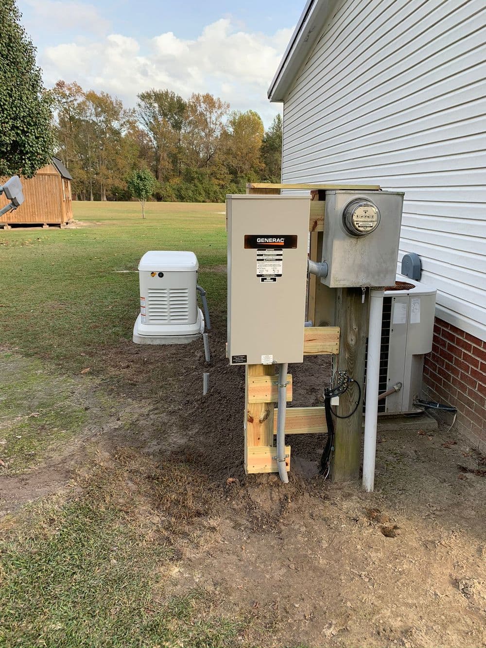 Generator installation outside a home with electrical connections and a grassy area.