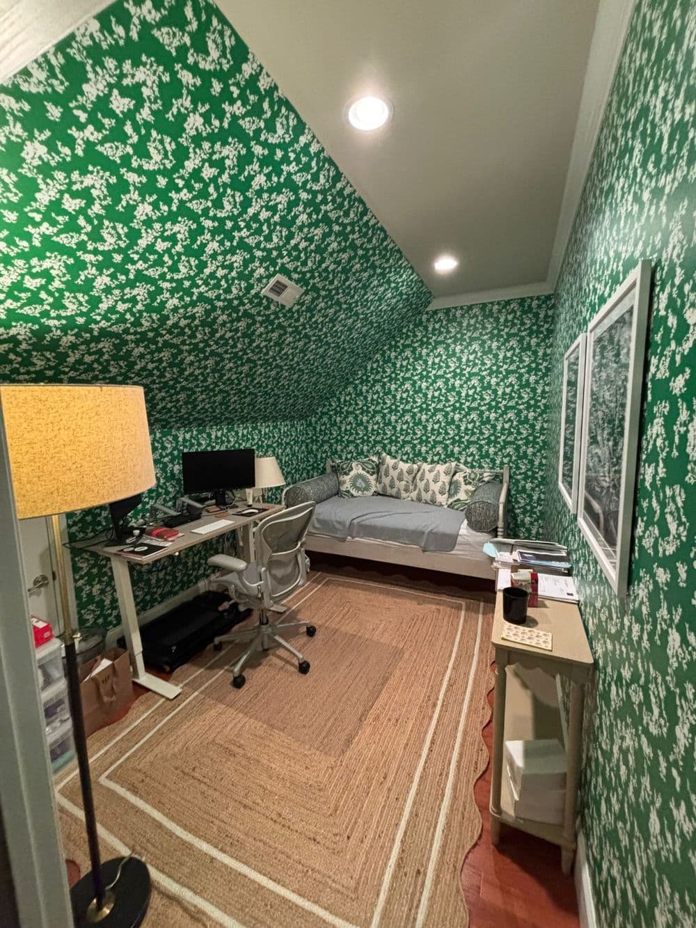 Cozy home office with green floral wallpaper, desk, and daybed in an attic space.