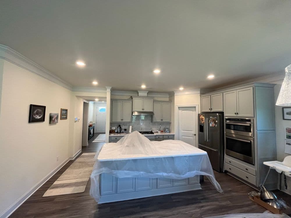 Modern kitchen under renovation with a large island, gray cabinetry, and bright lighting.