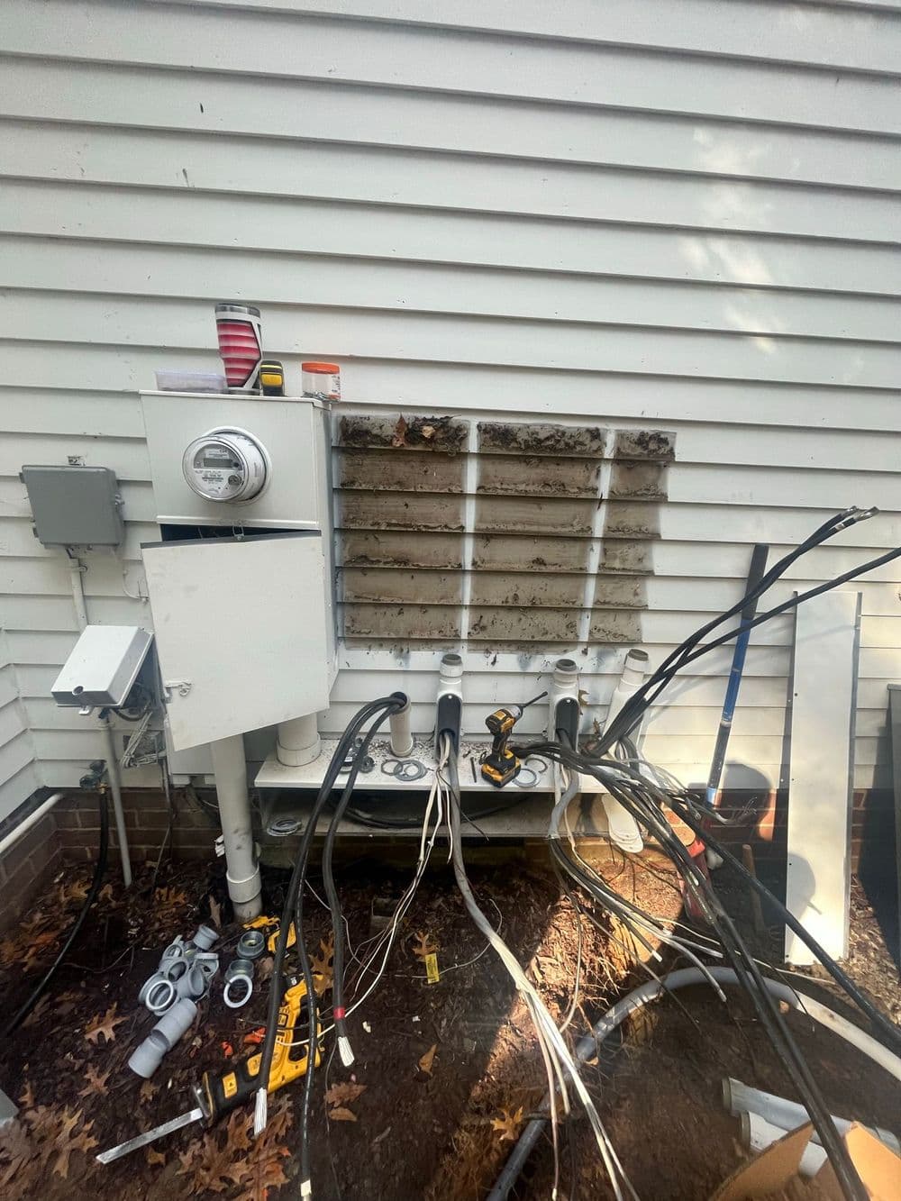 Air conditioning unit installation with exposed wiring and tools in a residential setting.