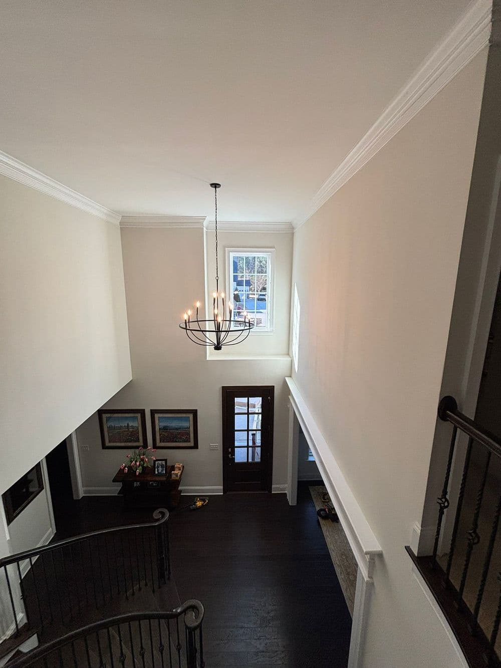 Spacious foyer with chandelier, dark wood floors, and elegant decor in a modern home.
