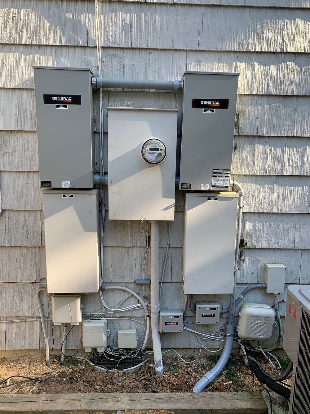 Electrical installation with multiple Generac equipment units on a house exterior wall.