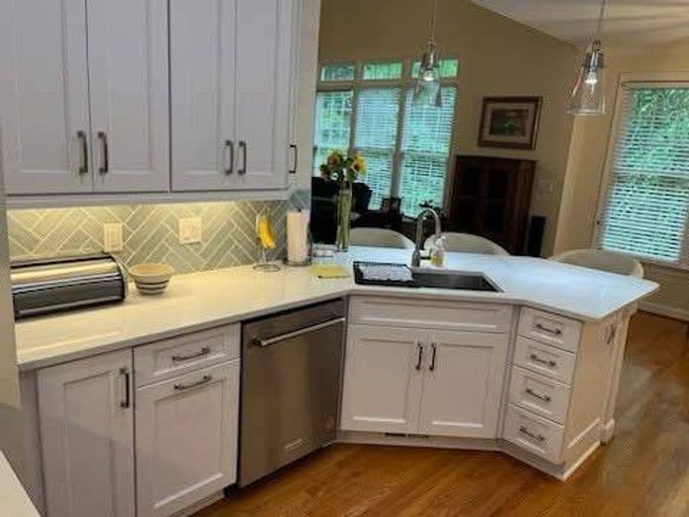 Modern kitchen with white cabinetry, quartz countertops, stainless steel appliances, and natural light.