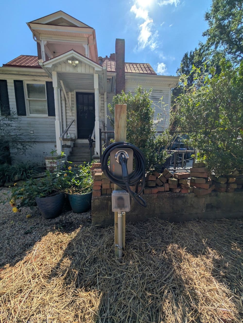 Home electric vehicle charging station installed in front yard with house in background.