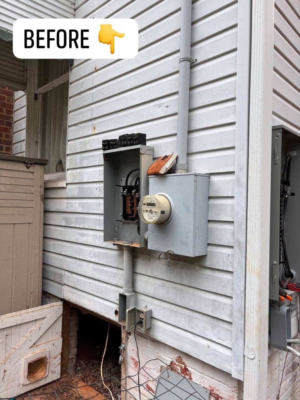 Electrical panel and meter on exterior wall, showing outdated setup before renovation.